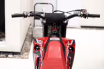 Red dirt bike handlebars and fuel tank front view