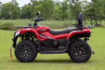 Red 4x4 ATV with black wheels parked on grass