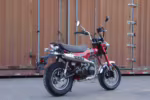 Red mini motorcycle parked by shipping container