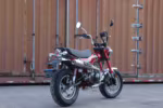 Red mini motorcycle parked by shipping container