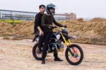 Dos personas montando una moto de cross con radios de colores.