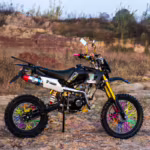 Moto de cross negra con radios de ruedas de colores en terreno rocoso