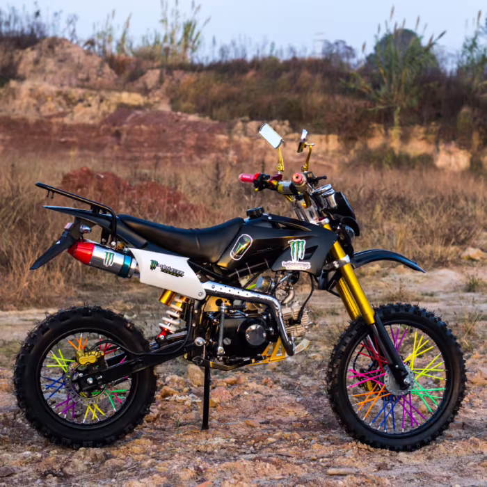 Moto preta de trilha com raios coloridos nas rodas em terreno rochoso