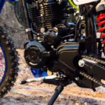 Motor de motocicleta preto com transmissão por corrente e pneu de cravos