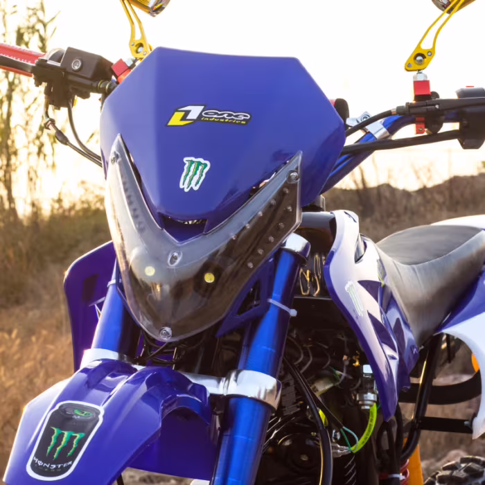 Motocicleta de motocross azul, vista frontal, com adesivos da Monster Energy.