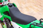 Primer plano del asiento y el depósito de combustible de una moto de cross verde.