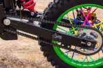 Rueda trasera de moto de cross con radios de colores y sistema de transmisión por cadena.