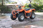 Quadriciclo laranja YKF-F1 200 em leito de rio rochoso