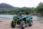 Quadriciclo azul e verde estacionado na margem rochosa do rio