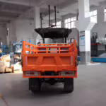 Vista trasera de un vehículo utilitario naranja en fábrica.