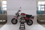 Mini motocicleta Gorilla vermelha e branca em suporte.