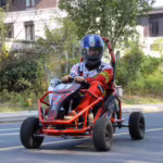 Person driving red off-road go-kart on street