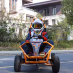 Rider in helmet driving orange off-road go-kart