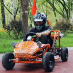 Person riding orange spider web go-kart outdoors