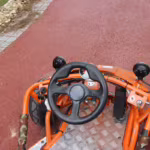 Orange go-kart steering wheel and dashboard view