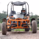 Orange off-road go-kart with driver on dirt track
