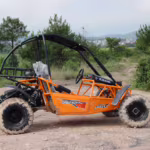 Orange off-road go-kart with roll cage on dirt path