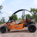 Orange off-road go-kart with roll cage on rocky terrain