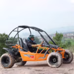 Orange off-road dune buggy with driver wearing helmet