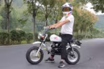 Rider on white Honda mini motorcycle on road