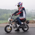 Motociclista em pequena motocicleta preta usando equipamento completo