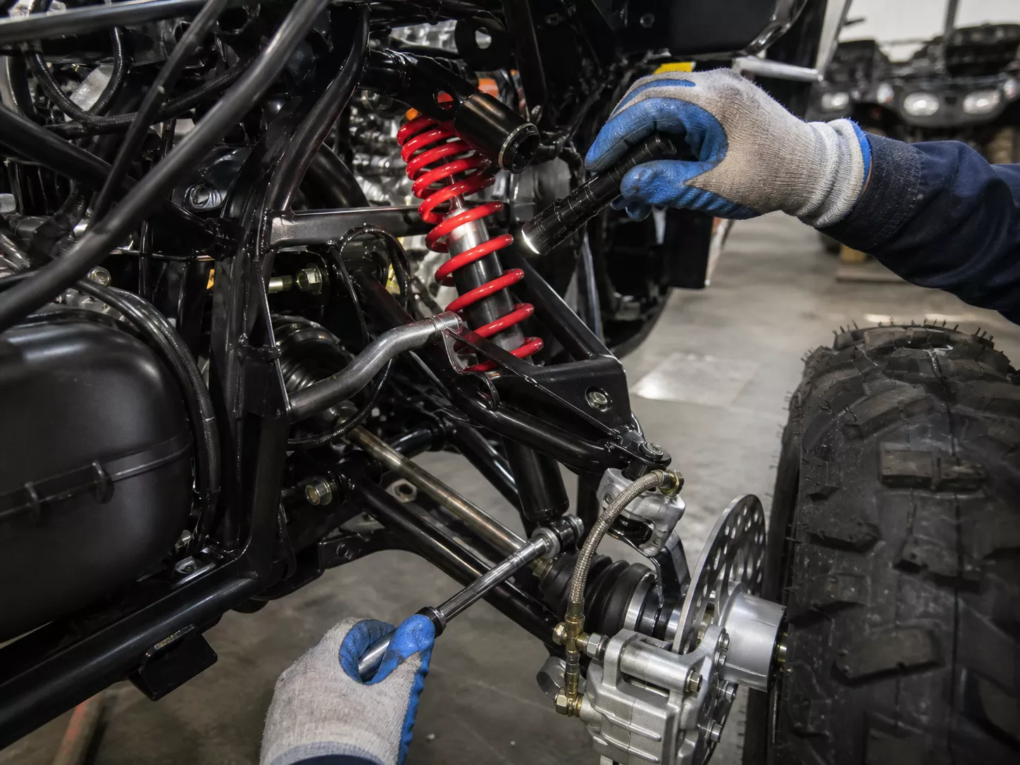 YKF MOTO technician checking ATV suspension and wheel hub during quality review